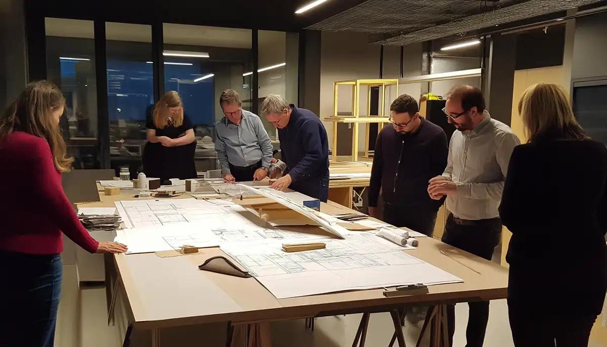 קבוצת מתכננים בוחנת תכניות בנייה לפי חלופת שק על שולחן (נוצר ב-AI)